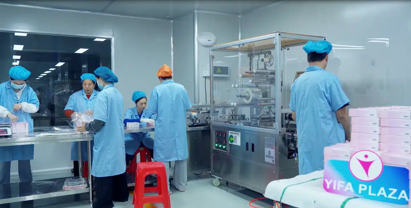 Cosmetic OEM workers operating a packaging line in a Guangzhou cleanroom
