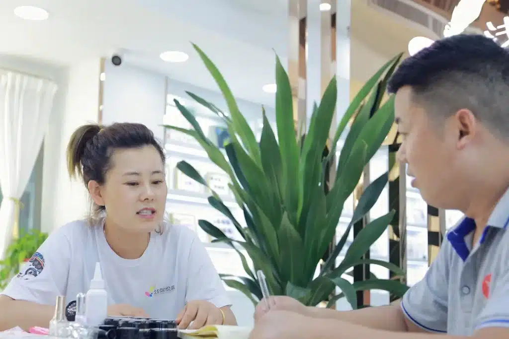 YIFA PLAZA sourcing staff discussing nail product samples with a buyer inside a Guangzhou beauty showroom