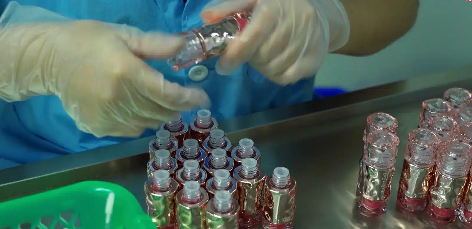 Cosmetic bottles being assembled and visually inspected by a worker at a supplier production line in Guangzhou